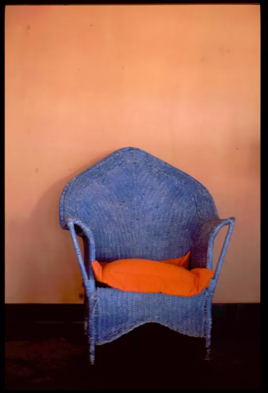 faded blue cair in front of cream colored wall