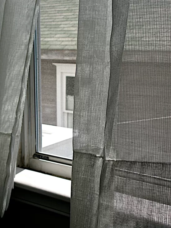 Open window with sheer grey curtain